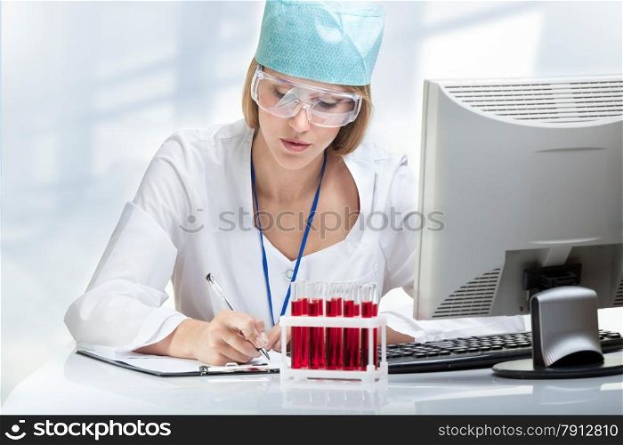Young woman scientist examining a test tube with blood