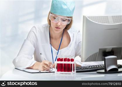 Young woman scientist examining a test tube with blood
