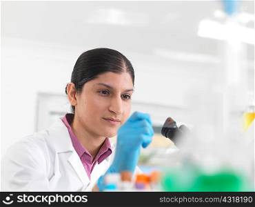 Young woman scientist viewing blood slide during clinical testing of medical samples in a laboratory