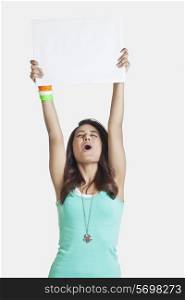 Young woman screaming while holding up a blank placard over white background