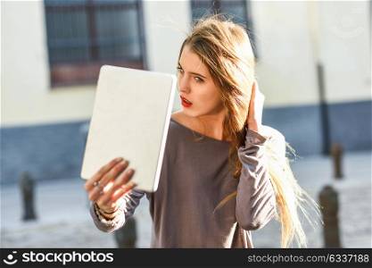 Young woman self looking at tablet in urban background