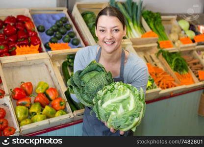 young woman seller weighing cabbage