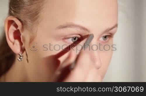 Young woman shaping her eyebrows.