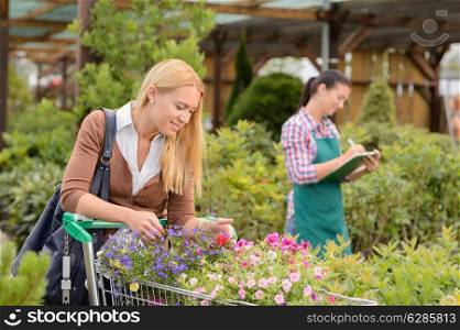 Young woman shopping cart for flowers at garden center smiling