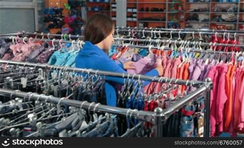 Young woman shopping for clothes in a clothing store, choosing jacket