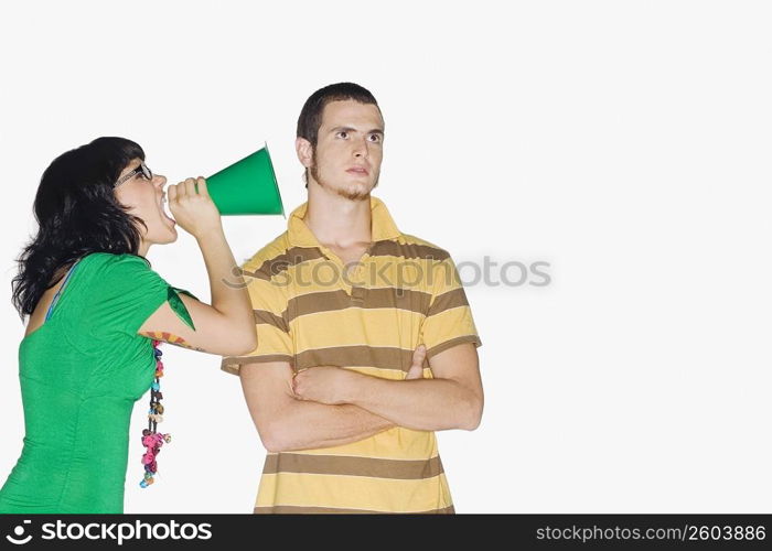 Young woman shouting with a megaphone into a young man&acute;s ear