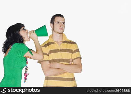 Young woman shouting with a megaphone into a young man&acute;s ear