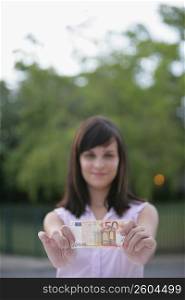 Young woman showing a fifty Euro banknote