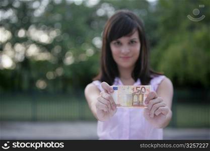 Young woman showing a fifty Euro banknote and smiling