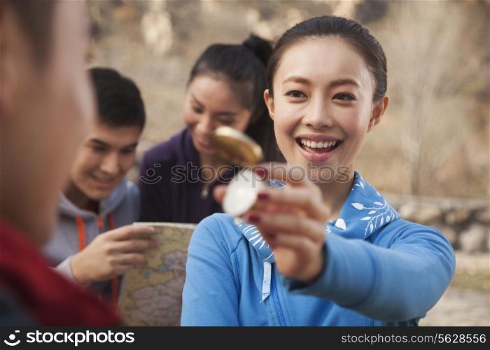 Young woman showing compass to her friend
