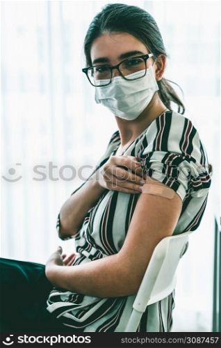 Young woman showing COVID-19 vaccine bandage merrily in concept of coronavirus vaccination program to vaccinate citizen .. Young woman showing COVID-19 vaccine bandage merrily
