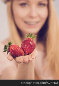 Young woman showing fresh strawberries fruits. Healthy meal. Toned image. Girl showing fresh strawberries