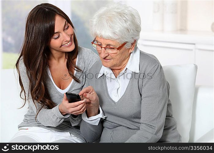 Young woman showing how to use mobile phone to grandmother