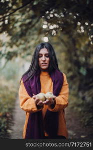 Young woman showing pears at the camera in the forest