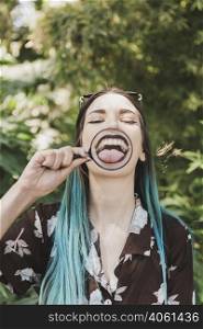 young woman showing tongue through magnifying glass