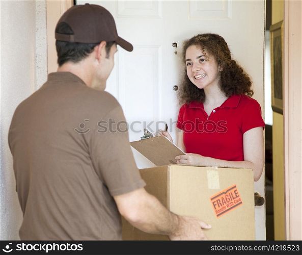 Young woman signs for a package delivered by a courier.