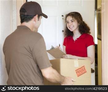 Young woman signs for a package delivered by a courier.