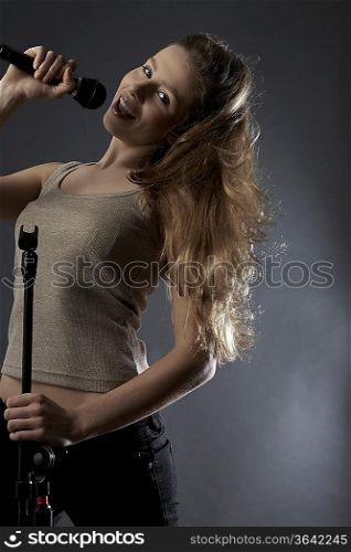 Young woman singing in studio, portrait