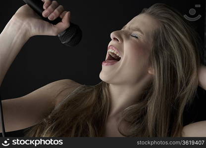 Young woman singing into microphone, close-up