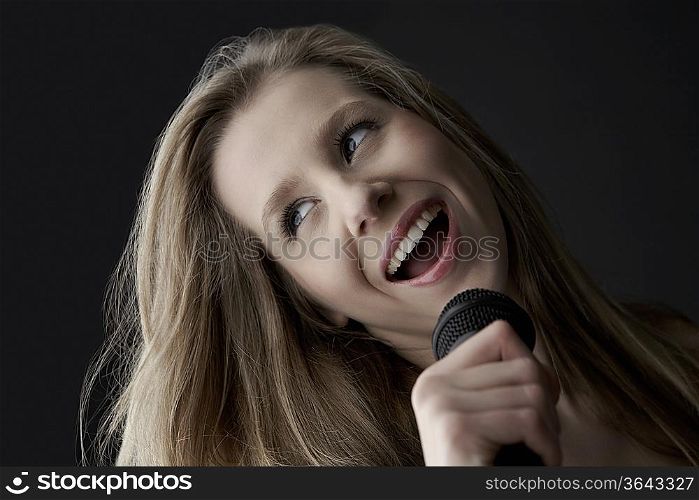Young woman singing into microphone, close-up