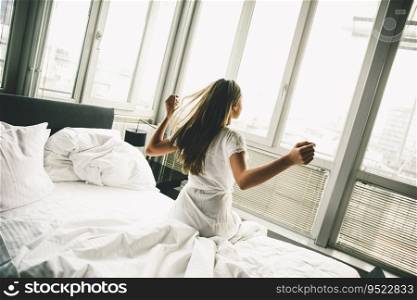 Young woman sits on a bed with white linen