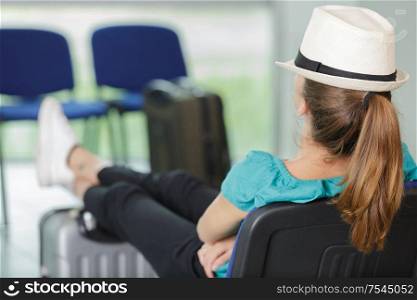 young woman sits on a suitcase in airport