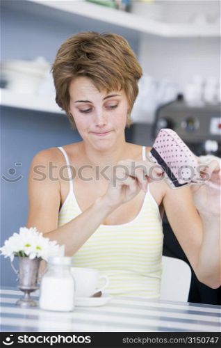 Young woman sitting at a table checking change purse