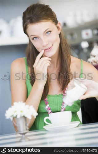 Young woman sitting at a table drinking tea