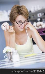 Young woman sitting at a table eating a sweet treat