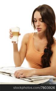 young woman sitting at a table reading newspaper holding latte macchiato coffee. young woman sitting at a table reading newspaper holding latte macchiato coffee on white background