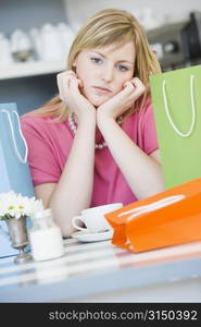 Young woman sitting at a table taking a break from shopping and drinking tea