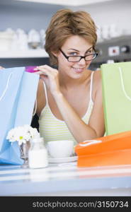 Young woman sitting at a table taking a break from shopping and drinking tea