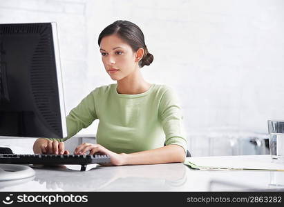 Young woman sitting at desk using computer