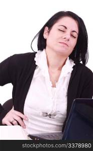 Young woman sitting at her laptop with a lot of work in front of her. She has a pain in her neck / back