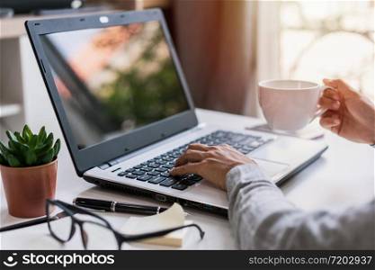 Young woman sitting at living room and working on laptop and smartphone at home