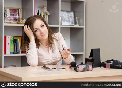 Young woman sitting at office table, laid out on the table cosmetics