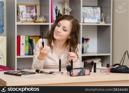 Young woman sitting at office table, laid out on the table cosmetics