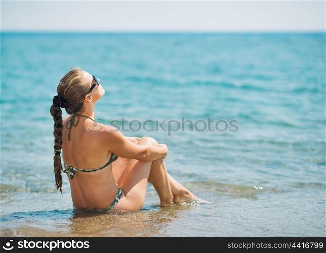 Young woman sitting at seaside . rear view