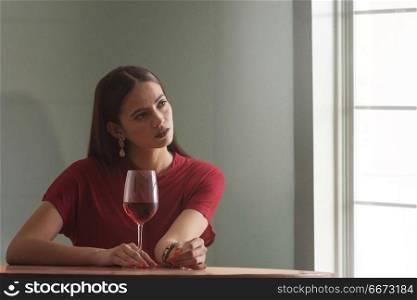 Young woman sitting at table with wine glass