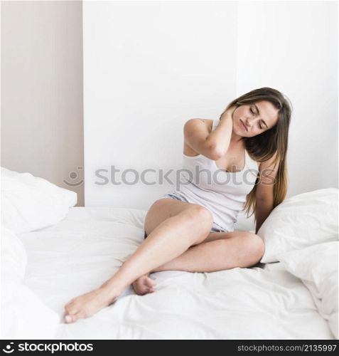 young woman sitting bed suffering from neck pain