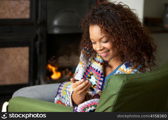 Young woman sitting by fire with phone