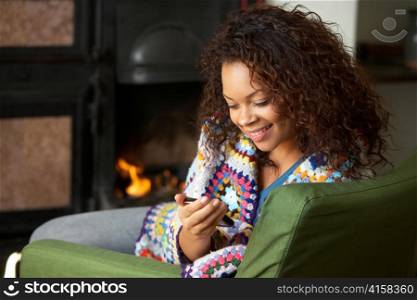 Young woman sitting by fire with phone