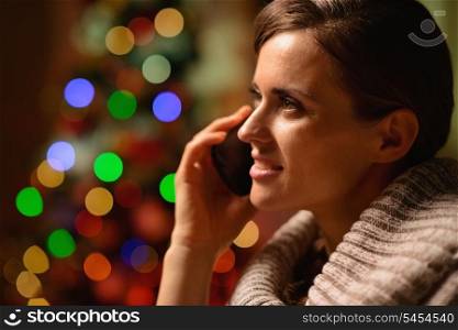 Young woman sitting chair and making phone call in front of Christmas lights