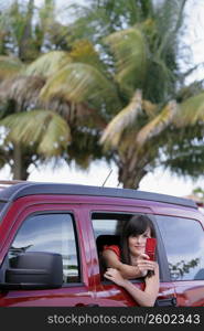 Young woman sitting in a car and taking a picture with a mobile phone