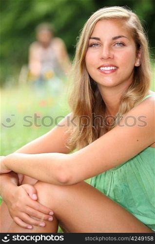 Young woman sitting in a meadow in the summertime