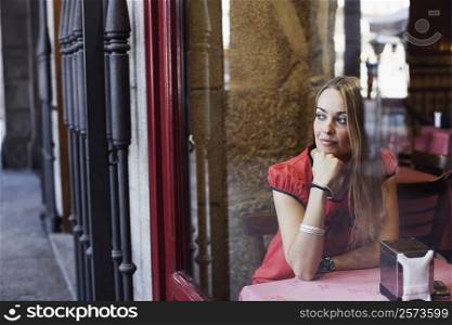 Young woman sitting in a restaurant with her hand on her chin