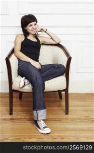 Young woman sitting in an armchair and talking on a mobile phone
