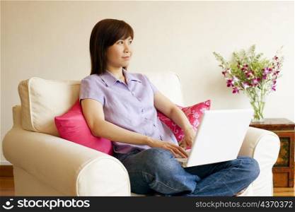 Young woman sitting in an armchair with a laptop