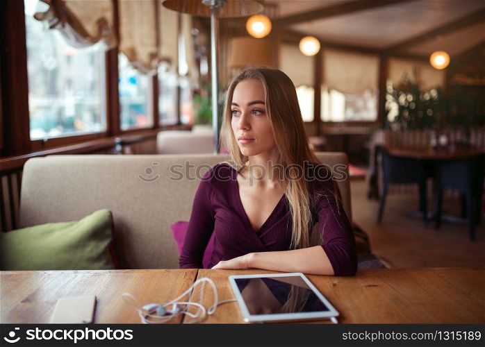 Young woman sitting in cafe. Tablet pc on the table.