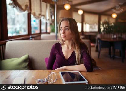 Young woman sitting in cafe. Tablet pc on the table.
